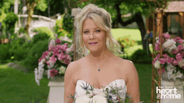a woman in a wedding dress holds a bouquet of flowers in front of a sign that says heart and home