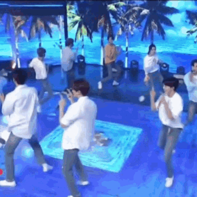 a group of men are dancing on a stage in front of a large screen .