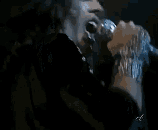 a woman is singing into a microphone while a man looks on .