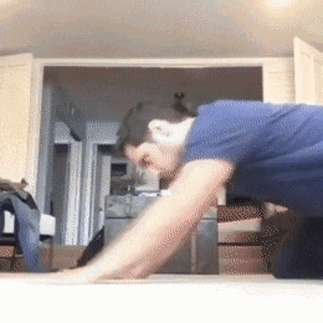 a man in a blue shirt is doing push ups in a living room