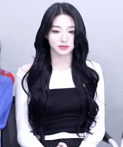 a woman with long black hair wearing a white shirt