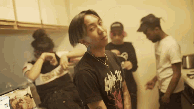 a man wearing a black t-shirt with a skull on it stands in front of a group of people