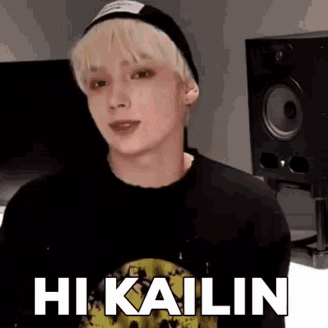 a young man with blonde hair is wearing a black hat and a black shirt and says hi kailin .