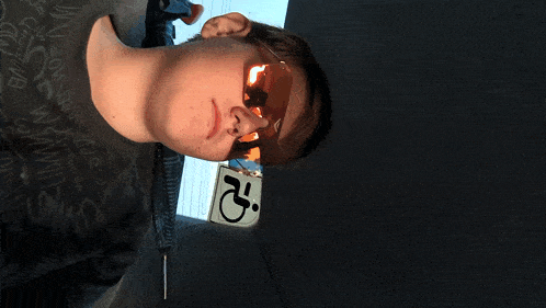 a man wearing sunglasses is standing next to a handicap sign