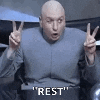 a bald man is sitting in a chair giving a peace sign .