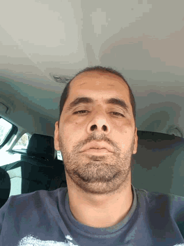 a man with a beard and a blue shirt is looking down