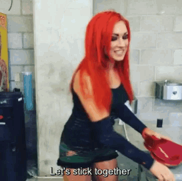 a woman with red hair is holding a red hat and saying " let 's stick together "