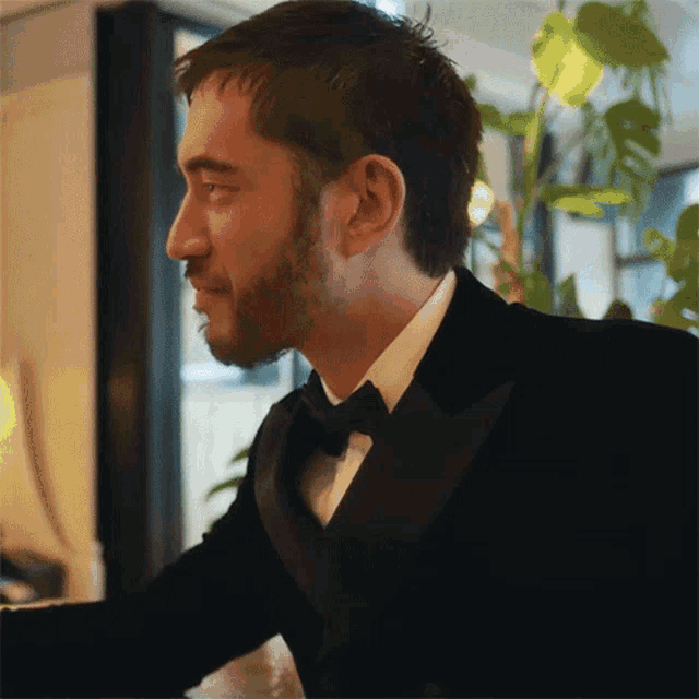 a man with a beard is wearing a black tuxedo and bow tie