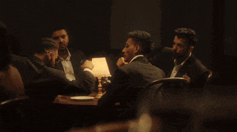 a group of men are sitting at a table with plates of food