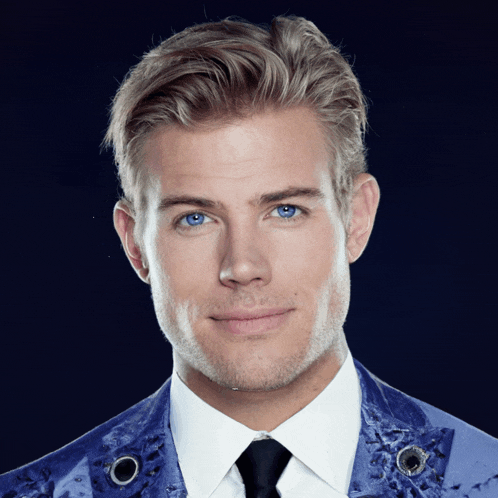 a man with blue eyes is wearing a white shirt and a blue jacket