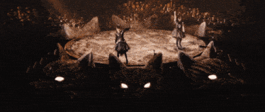 a woman in a black dress is dancing on a stage in a dark room