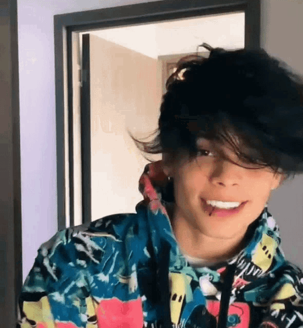 a young man with a piercing in his tongue is wearing a colorful hoodie .