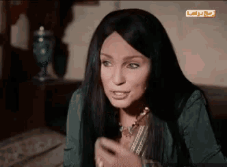 a woman with long black hair is sitting on a bed in front of a sign that says " drama "