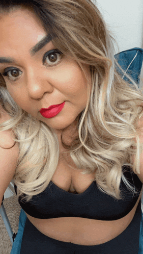 a woman with blonde hair and red lipstick is taking a selfie