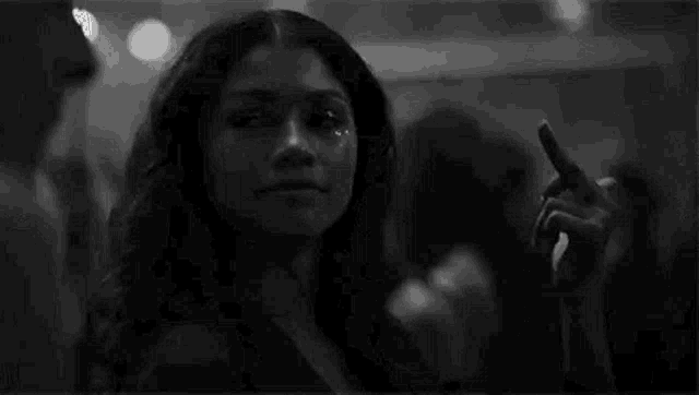 a black and white photo of a woman taking a selfie in a crowd .
