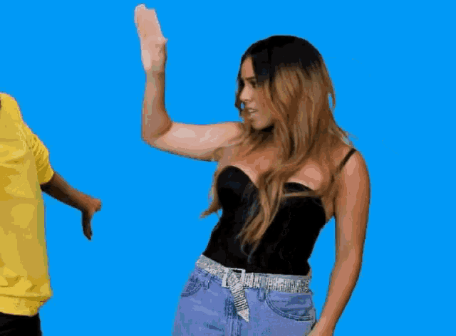 a woman in a black top is dancing with a man in a yellow shirt behind her