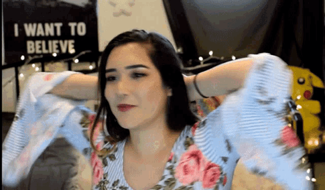 a woman with her arms outstretched in front of a sign that says i want to believe