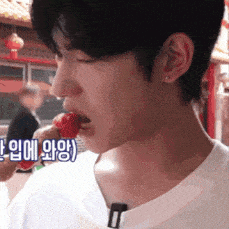 a close up of a person eating a strawberry with chinese writing on the bottom right