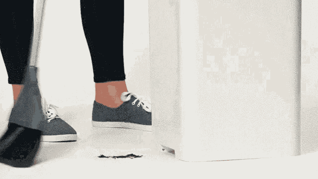 a person is using a broom to clean the floor