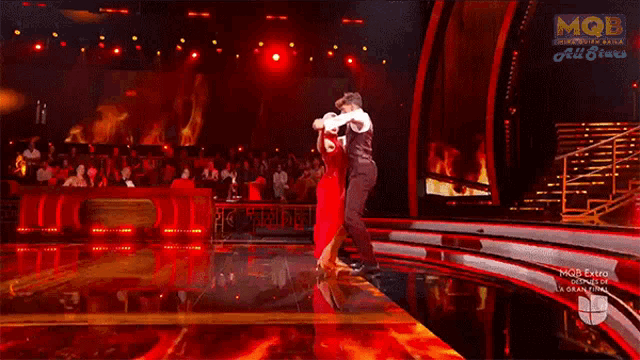 a man and a woman are dancing in front of a sign that says mgb entretenimiento