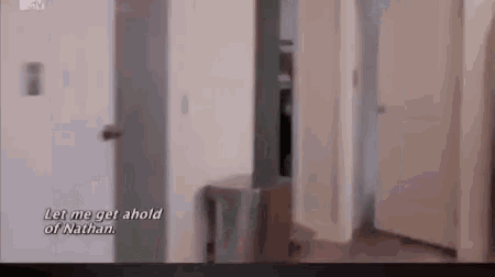 a person is standing in a hallway next to a door and talking to a person .