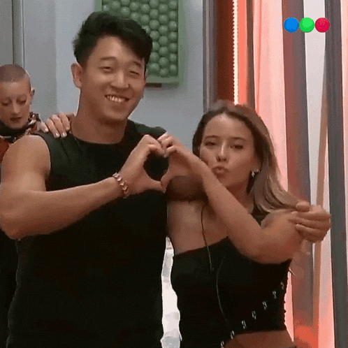 a man and woman make a heart shape with their hands