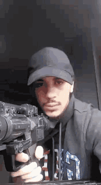a man wearing a hat is holding a gun in his hand .