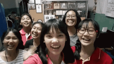 a group of young girls are posing for a selfie in front of a wall with a calendar on it