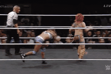 two women are wrestling in a wrestling ring with a referee watching