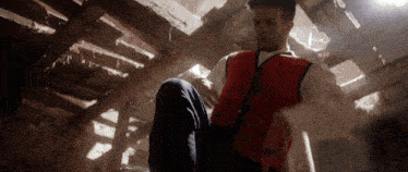 a man in a red vest is kneeling down in a dark room
