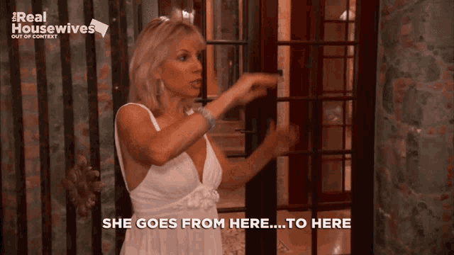 a woman in a white dress is pointing at a door and says she goes from here to here