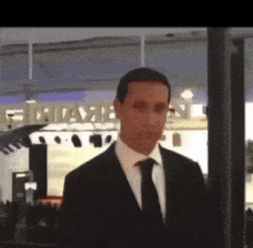 a man in a suit and tie is in front of a sign that says miami