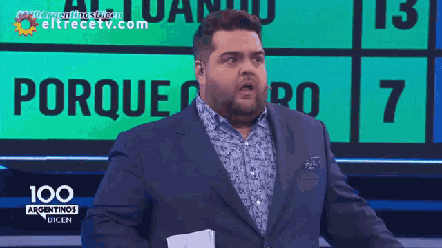 a man in a suit stands in front of a scoreboard that says porque