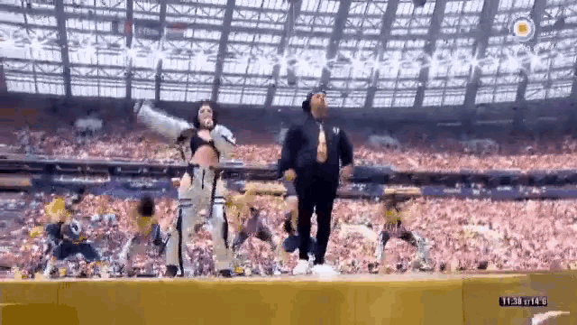 a man and a woman are dancing on a stage in front of a crowd in a stadium .