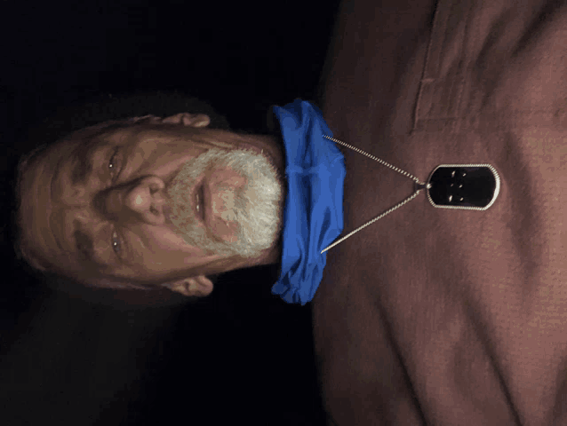 a man wearing a dog tag and a blue scarf around his neck