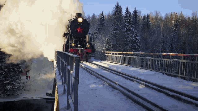 a train with a red star on the front is going over a snowy bridge