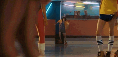 a group of people are rollerblading in a rink with a man watching