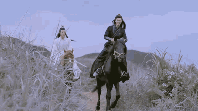 two men riding horses in a grassy field