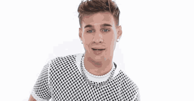 a young man wearing a black and white mesh shirt and a pearl necklace .