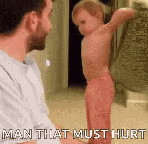 a man is holding a baby in his arms while a baby stands next to him .