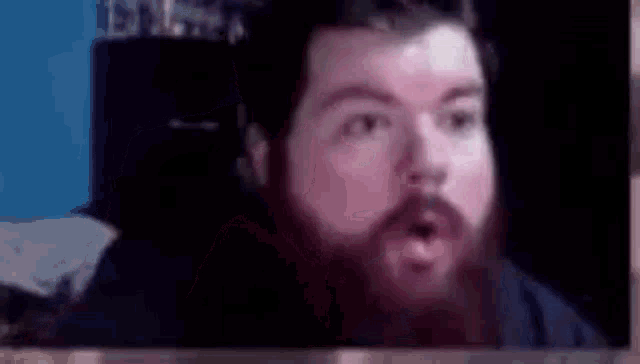 a man with a beard is making a surprised face while looking at the camera .