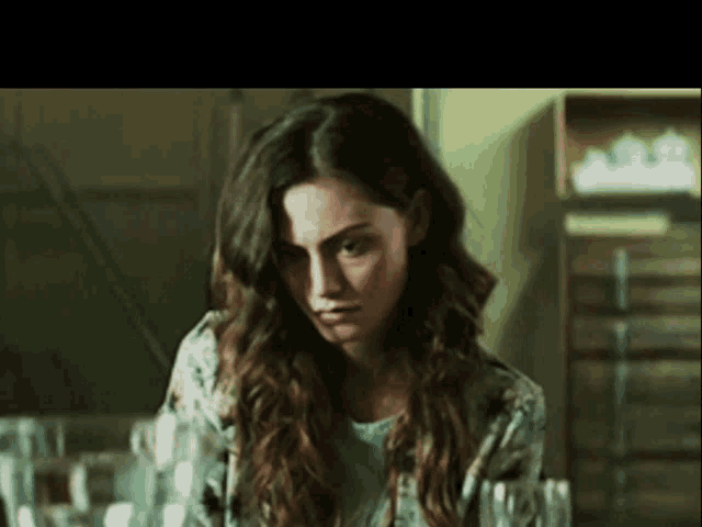a woman in a floral shirt is looking down at something