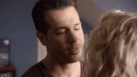 a man is kissing a woman on the cheek in a bedroom .
