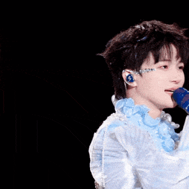 a close up of a person holding a microphone with the letter s on their ear