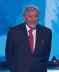 a man in a suit and tie is standing in front of a blue background