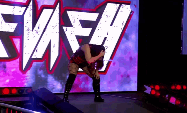 a female wrestler is kneeling down in front of a large screen that says ewfh