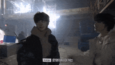 a man in a black jacket is standing next to another man in a white jacket and says " keiju " at the bottom