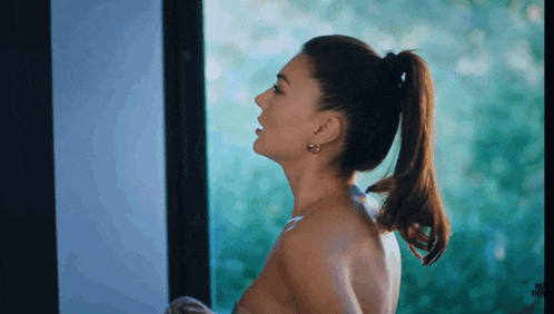 a woman with a ponytail is standing in front of a window .
