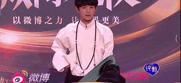 a man in a white shirt is standing in front of a sign with chinese writing on it