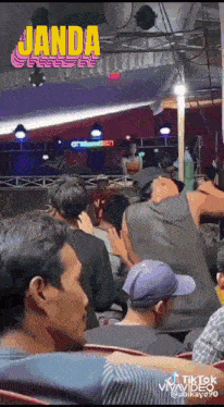 a group of people are sitting in front of a stage with a sign that says ' janda ' on it